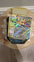 Top view of a stack of various Pokemon cards including a holographic Zacian V card and a Porygon card in the front, all stored in a metal tin.