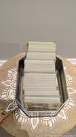 Stacked Pokemon cards in a metal tin from a side angle showing card thickness and storage method.