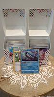 Two open boxes with multiple Japanese Pokémon cards standing up side-by-side on a surface showing front card designs.