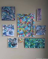Photo showing the 8 original abstract paintings from the Blue Collection by Jose Laberge, arranged on a wall, varying in size and featuring blue and multicolor abstract designs.