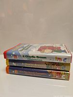 Stack of three VHS tapes with titles A Charlie Brown Christmas, A Charlie Brown Thanksgiving, and It’s the Great Pumpkin Charlie Brown visible on the spine and front covers.