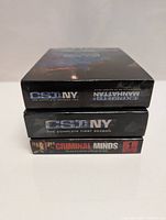 Stacked DVD box sets: CSI NY Season 2 on top, CSI NY Season 1 middle, Criminal Minds Season 1 bottom.