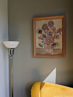 Framed reproduction of Van Gogh's The Sunflowers painting mounted on a wall, showing oak wood frame and part of surrounding room.