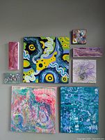 Photo shows 8 original abstract paintings by Jose Laberge in various sizes and vibrant colors arranged on a surface.