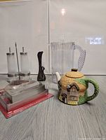 Photo showing all items in the lot including brass swan vase, Staffordshire cottage teapot, juice pitcher, oil and vinegar dispenser set and gingerbread house cutter.