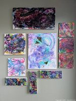 Photo showing 10 original abstract paintings of varying sizes with dominant purple, blue, black and other colors, mounted on a wall for display.