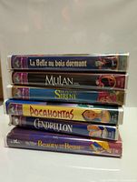 Stack of 6 Disney Classics VHS tapes all with purple Disney Classics cases showing French and English princess titles