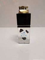 Front view of the lighter showing minerals suspended in clear glass base with black cube and brass lighter mechanism.