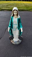 Front view of the statue showing Virgin Mary with open hands and Miraculous Medals near the base.
