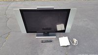 Front view of 40 inch SONIQ Ultra LCD HDTV television with remote and antenna placed on ground.