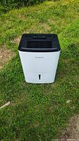 Frigidaire humidifier displayed on grass showing front view with water level window and brand name.