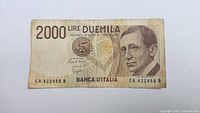 Front side of a 2000 Lire banknote from Italy featuring a portrait of a man, serial number CA 422458 B.