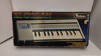 Front view of the boxed vintage Bontempi B1 keyboard piano showing wear on the box.