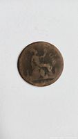 Reverse side of UK bronze 1 penny coin showing seated Britannia holding trident, with worn condition