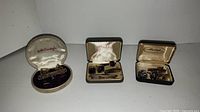 Photo of three jewelry boxes containing vintage cufflinks and tie clips.