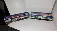 Two vintage Hess toy trucks in original boxes, one fire truck and one toy truck with helicopter.
