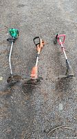 Photo showing three gasoline weed wackers placed on ground, two missing bottom spindles.