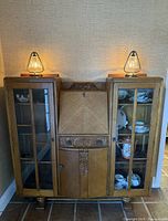 Full front view of the antique carved oak secretary bookcase showing glass-paneled doors, central drop front desk, and carved details.