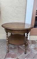 Photo of antique oval end table showing top surface, bobbin spindle legs, and lower shelf with visible wear on top.