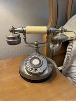 Side angle photo showing the phone on a wooden surface with visible rotary dial and ivory-colored handset grips.