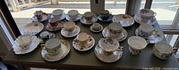 Wide view of all antique teacups and saucers arranged on table, showing variety and colors