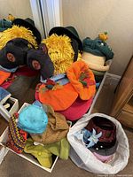 Photo showing a pile of vintage hats, including yellow pom-pom styled hats, orange pumpkin-like hats, teal felt hats with netting, and knitted beige hats.
