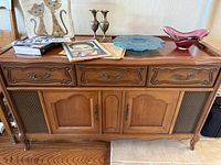 Front view of vintage wooden stereo cabinet with two drawers, two cupboards, and decorative sides.