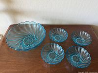 Top view of one large bowl and four smaller bowls showing the swirl pattern and scalloped edges.