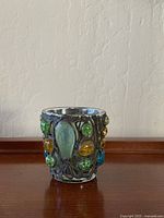 Front view of candle holder showing blue, green and amber Lucite stones embedded in metallic frame