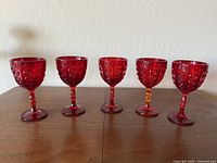 Front view of five Viking Art Glass Yesteryear ruby red bullseye chalices aligned in a row on a wooden surface.
