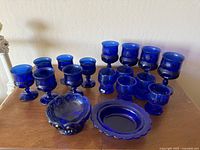 Front view of all items in the set including goblets, bowl, and plate arranged on wooden surface.