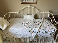 Full view of the vintage white iron day bed made with decorative castings and bedding, showing overall condition and style.