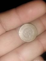 Photo showing the reverse side of a worn Indian Head cent featuring the words 'One Cent' with visible coin texture.