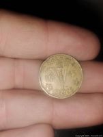 Front side of 1943 Canadian V nickel coin showing torch design, year, and maple leaves.