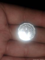 Reverse side of 1945 Canadian 5 cent coin showing the maple leaves cluster, the date 1945 and denomination '5' surrounded by beaded edge, held in a hand under direct light.