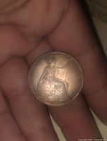 Reverse side of 1912 English penny with Britannia seated holding shield and trident.