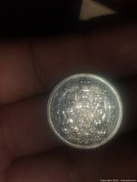 Reverse side of the coin showing the Canadian coat of arms with inscription.