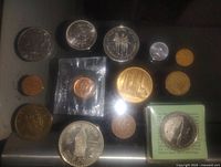 Overhead photo of coin collection showing variety of silver, gold, and bronze coins including sealed and cased coins