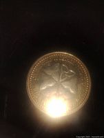 Close-up of medallion side showing floral emblem and surrounding text.