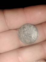 Coin showing the seated Britannia figure with 'FARTHING' inscription and date 1905, held in hand.