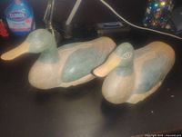 Pair of large carved wooden duck decoys side by side showing top and side carving detail and paint