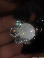 Close-up view of the brooch watch face with decorative crystal accents and signed dial.