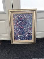 Gold-toned carved frame with multicolor marbled picture inside.