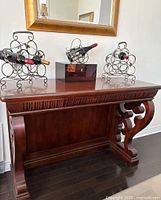 Photo showing mahogany finish bar console table with curved leg supports and decorative carved front panel.