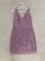 Front view of pink floral lace sleeveless dress laid flat on carpet showing texture and style
