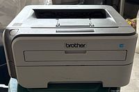 Front view of Brother printer showing logo, paper output tray, and general condition.