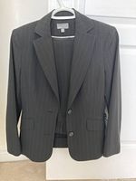Front view of the dark pinstripe women's jacket with two-button closure and flap pockets