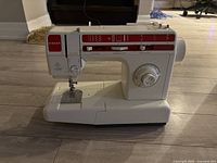 White and red Singer sewing machine showing stitch pattern controls and front profile