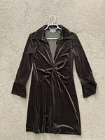 Dark brown velvet long-sleeve dress by Calvin Klein shown on hanger with front twist, collar, and cuffed sleeves.