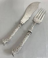 Pair of antique fish serving cutlery – knife and fork, showing their full shape and ornate engraving on handles and blades